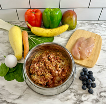 Load image into Gallery viewer, Raw dog food in a metal bowl with ingredients around bowl on a marble countertop.